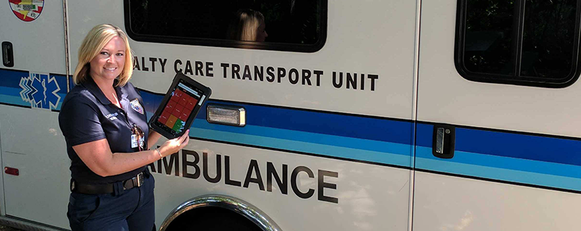 Nurse with tablet in front of ambulance
